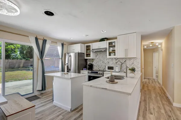 a kitchen with stainless steel appliances kitchen island granite countertop a refrigerator a stove and a wooden floors
