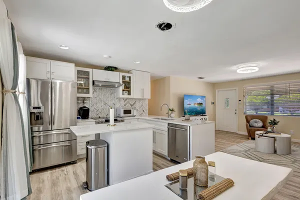 a kitchen with stainless steel appliances a refrigerator a sink a stove top oven a dining table and chairs