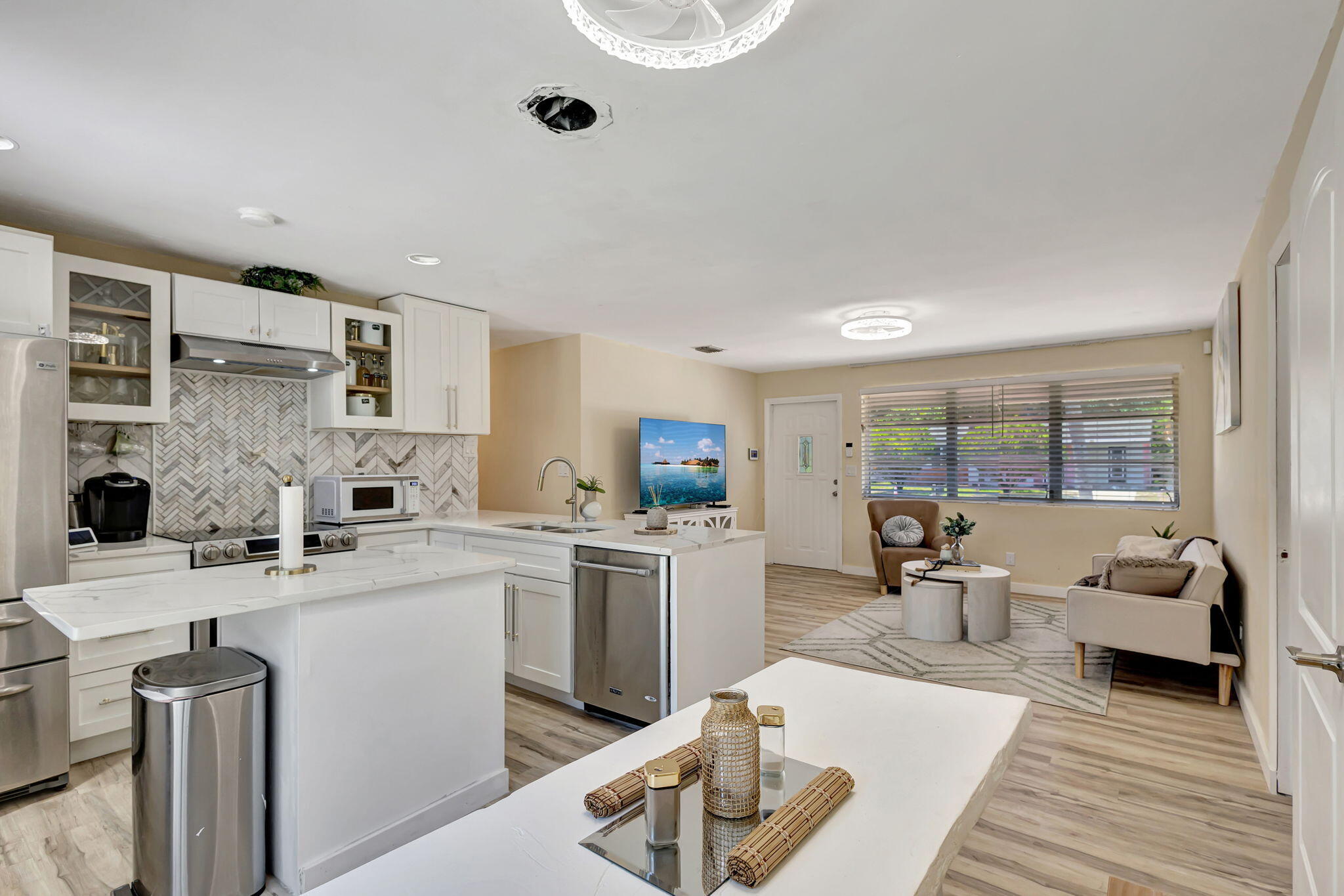 140 West 31st Court Riviera Beach, FL 33404 - Photo 29 of 43 a open kitchen with stainless steel appliances kitchen island granite countertop a sink dishwasher stove and white cabinets with wooden floor