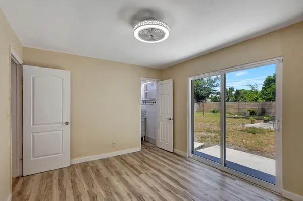 a view of empty room with wooden floor and fan