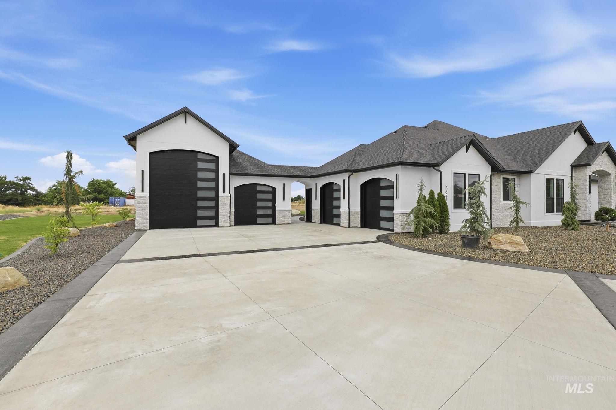 2321 Lower Bluff Road Emmett, ID 83617 - Photo 29 of 31 Contemporary ranch-style residence featuring a white stucco exterior, dark shingle roof, and an attached two-story structure
