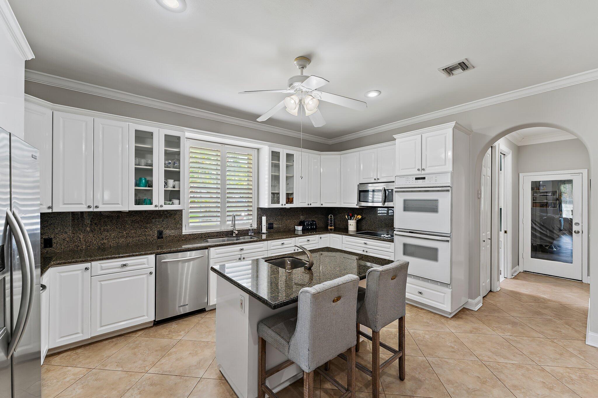 18263 River Oaks Drive Jupiter, FL 33458 - Photo 21 of 49 a kitchen with granite countertop a sink and white cabinets