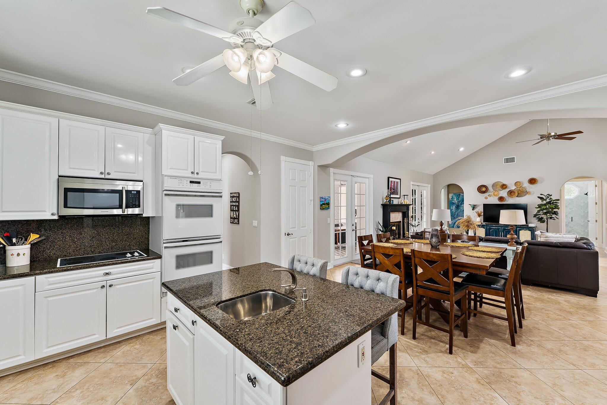 18263 River Oaks Drive Jupiter, FL 33458 - Photo 22 of 49 a kitchen with stainless steel appliances granite countertop a sink a stove a dining table and chairs