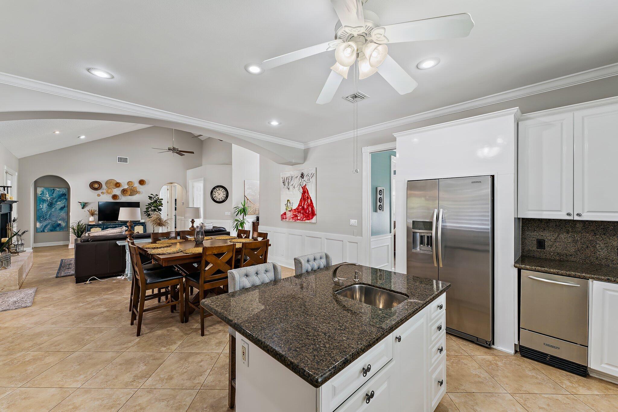 18263 River Oaks Drive Jupiter, FL 33458 - Photo 23 of 49 a kitchen with stainless steel appliances granite countertop a table chairs sink and refrigerator
