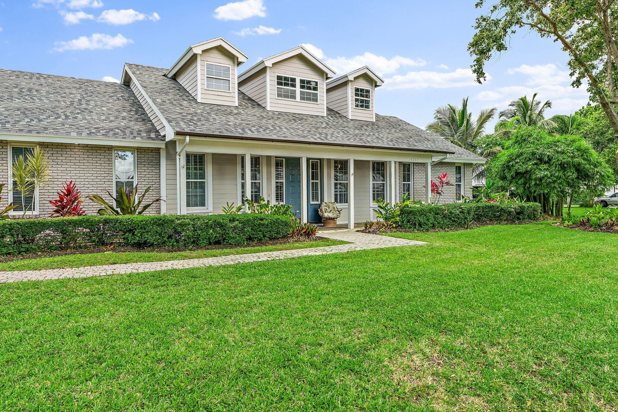 18263 River Oaks Drive Jupiter, FL 33458 - Photo 3 of 49 a front view of a house with garden