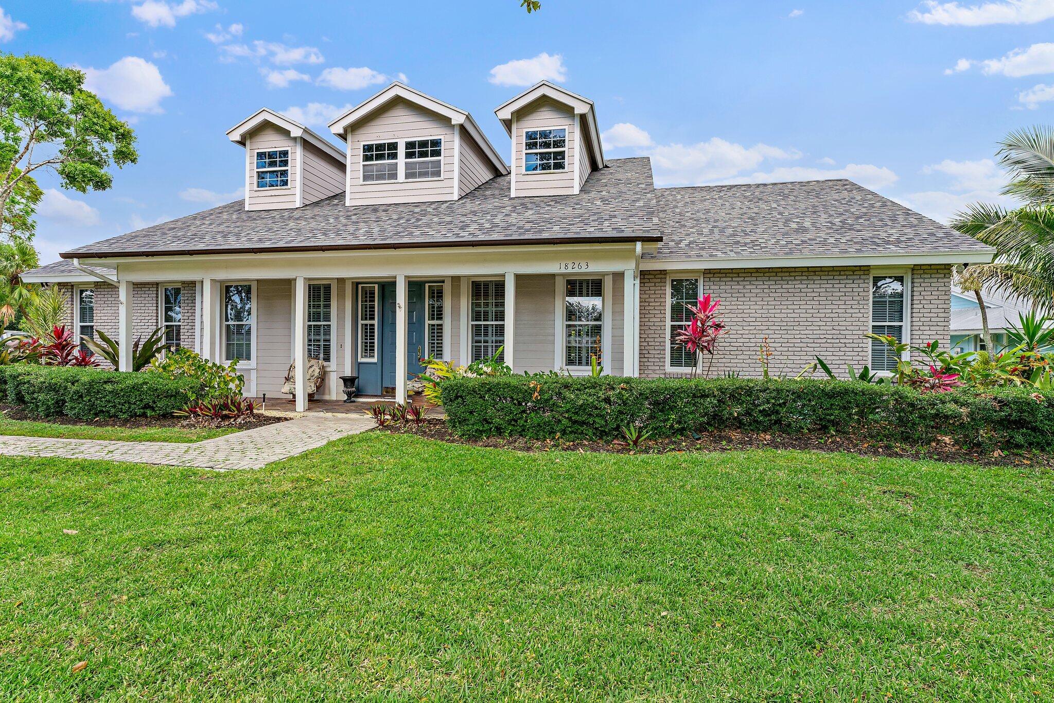 18263 River Oaks Drive Jupiter, FL 33458 - Photo 4 of 49 a front view of a house with garden and porch