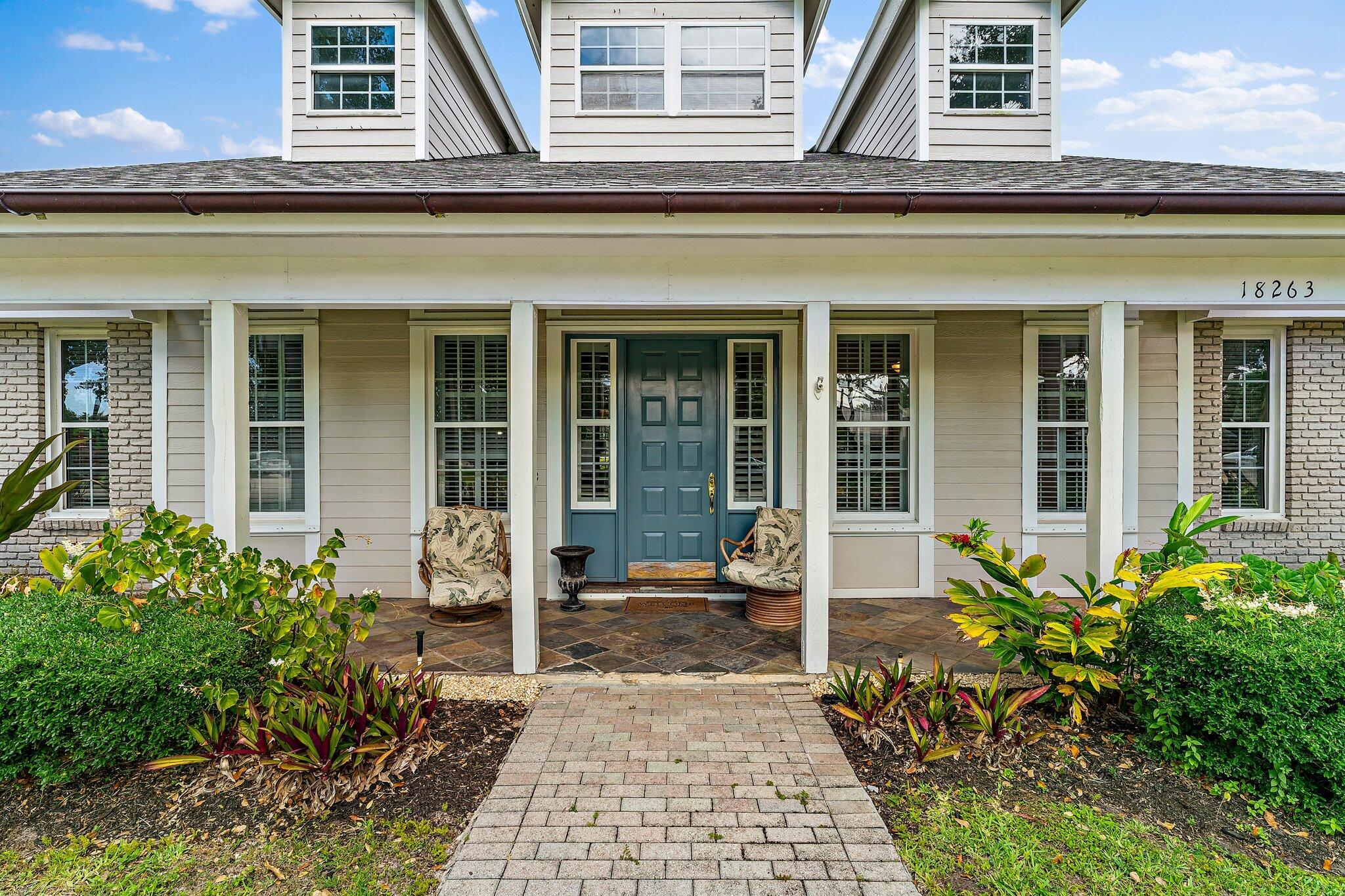 18263 River Oaks Drive Jupiter, FL 33458 - Photo 5 of 49 front view of a brick house with potted plants