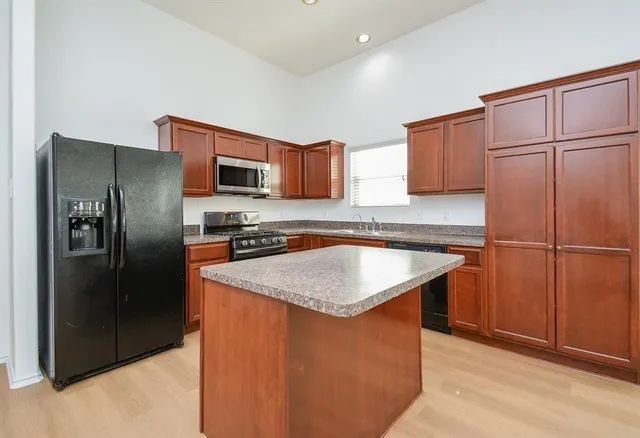 a kitchen with stainless steel appliances granite countertop a refrigerator a sink a stove a microwave and island