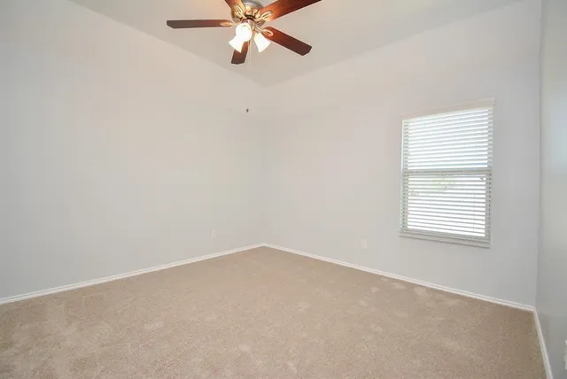 an empty room with a window and a fan