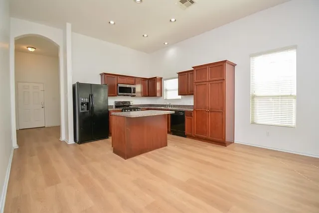 a kitchen with stainless steel appliances kitchen island granite countertop a refrigerator and a stove top oven