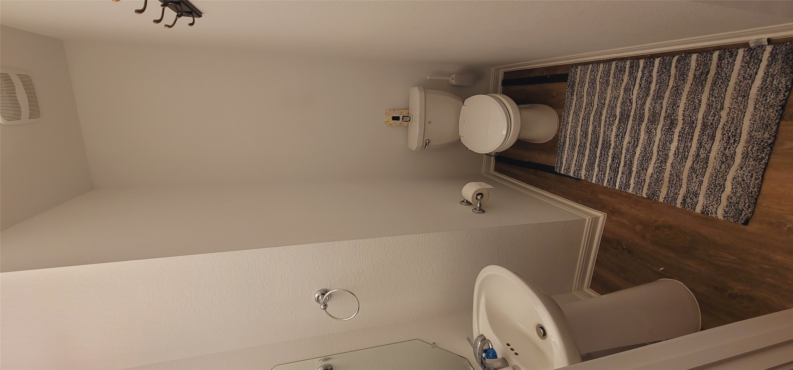 716 Leeward Pass Leander, TX 78641 - Photo 20 of 26 A compact powder room with wood flooring and a classic pedestal sink, offering functional design.