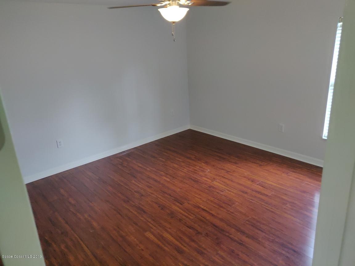 2025 Benjamin Road Grant Valkaria, FL 32950 - Photo 34 of 40 a big room with wooden floor a chandelier fan and windows