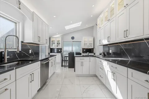 a kitchen with granite countertop a sink stainless steel appliances and white cabinets