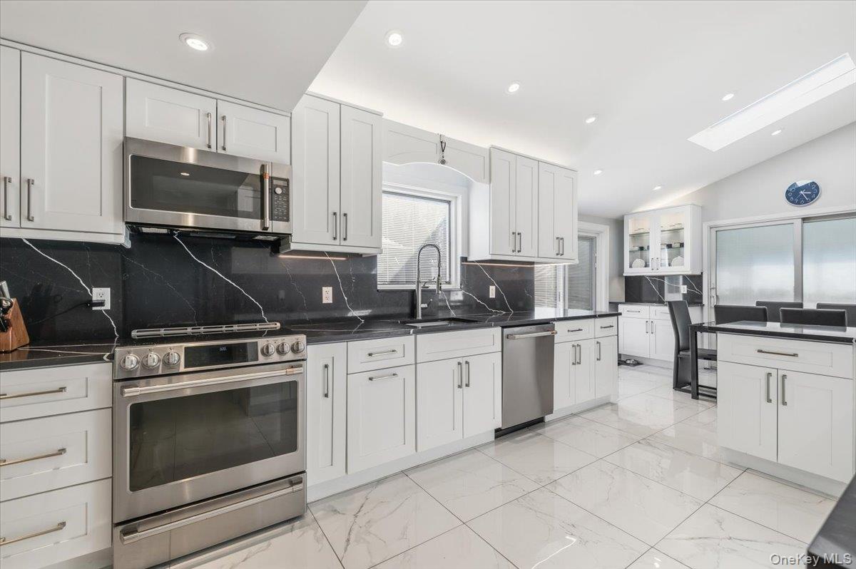 98 Barry Lane Syosset, NY 11791 - Photo 13 of 43 a kitchen with stainless steel appliances granite countertop a stove top oven a sink dishwasher and a refrigerator