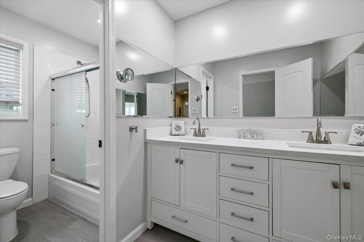 98 Barry Lane Syosset, NY 11791 - Photo 24 of 43 a bathroom with a toilet a double vanity sink a mirror and a shower