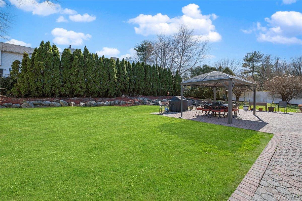 98 Barry Lane Syosset, NY 11791 - Photo 39 of 43 a view of a patio with table and chairs under an umbrella