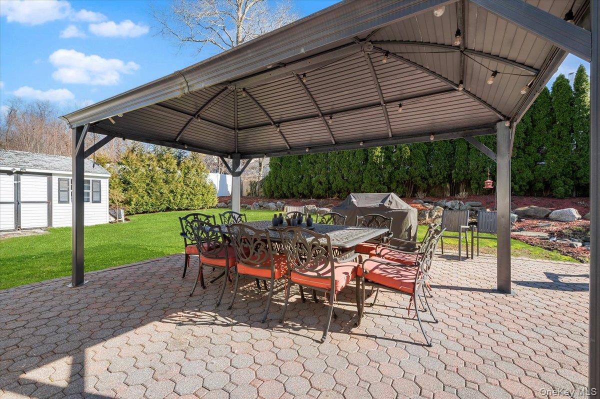 98 Barry Lane Syosset, NY 11791 - Photo 40 of 43 a view of a patio with a table and chairs under an umbrella