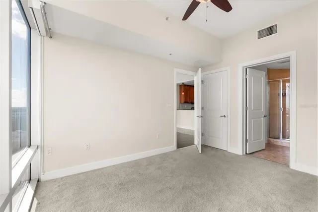 an empty room with ceiling fan and window