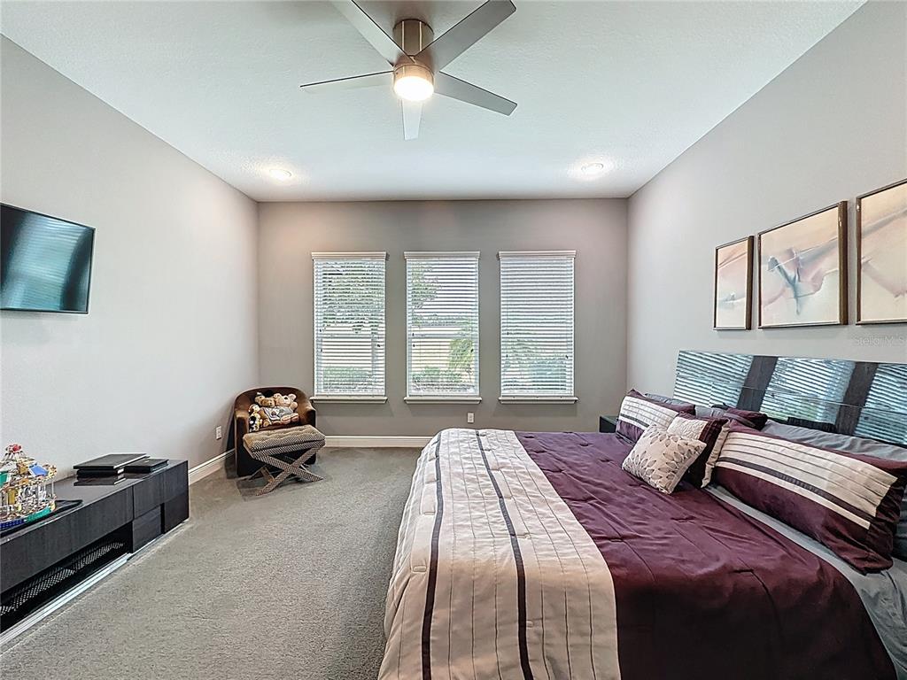 107 Balmy Coast Road Groveland, FL 34736 - Photo 36 of 97 a spacious bedroom with a bed and a chandelier