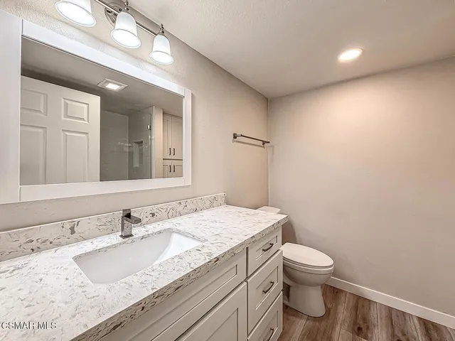a bathroom with a granite countertop sink a toilet and a mirror