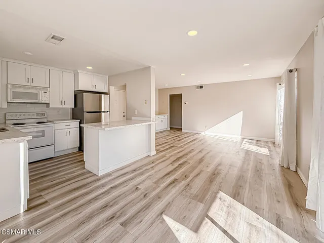 a view of a kitchen with wooden floor and electronic appliances