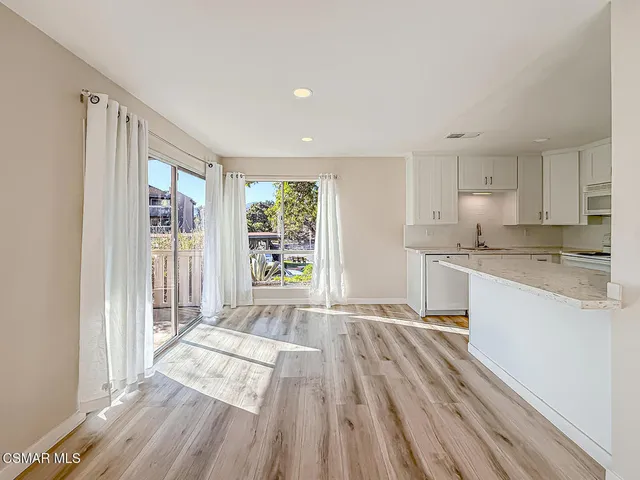 a large white kitchen with granite countertop a lot of counter space and wooden floor