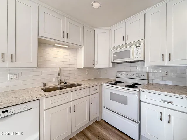 a kitchen with white cabinets and white appliances