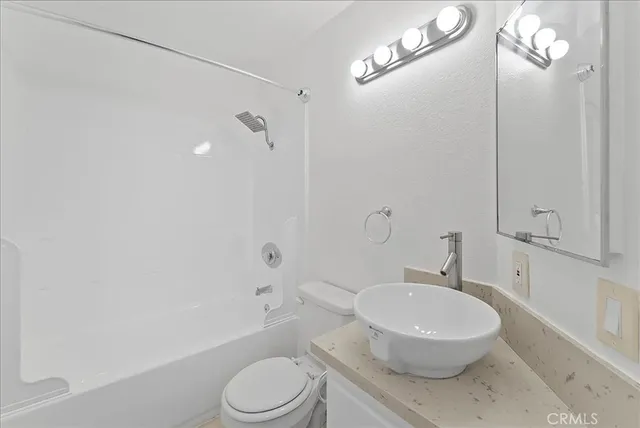 a white toilet sitting next to a bathroom sink and tub