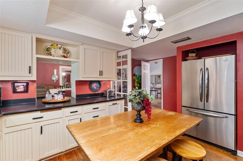 11427 Southwest 10th Terrace Micanopy, FL 32667 - Photo 29 of 77 a kitchen with stainless steel appliances granite countertop a refrigerator a sink dishwasher a dining table and chairs with wooden floor