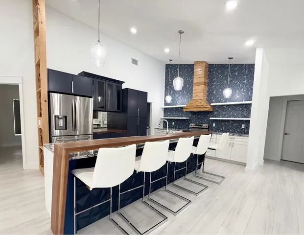 a large kitchen with a table chairs refrigerator and cabinets