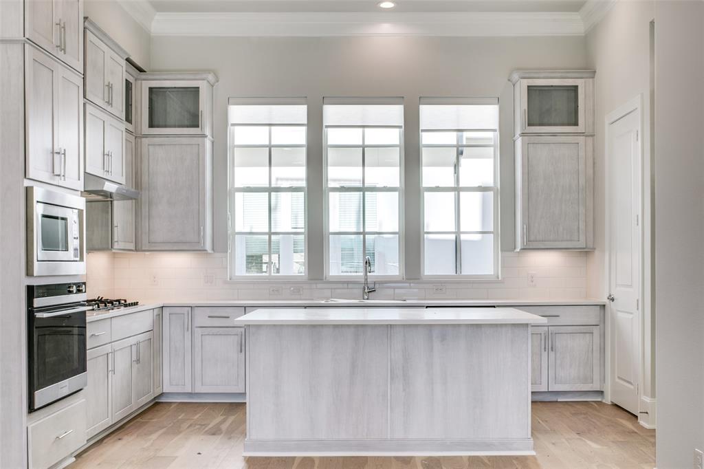 a white kitchen with granite countertop a stove and a sink