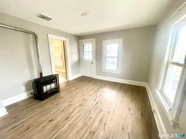 an empty room with wooden floor and windows