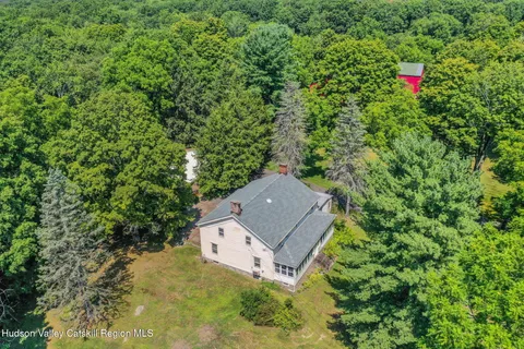 an aerial view of a house with yard and trees in the background