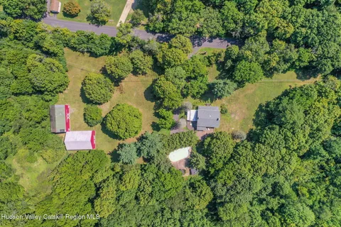 an aerial view of residential house with outdoor space and trees all around