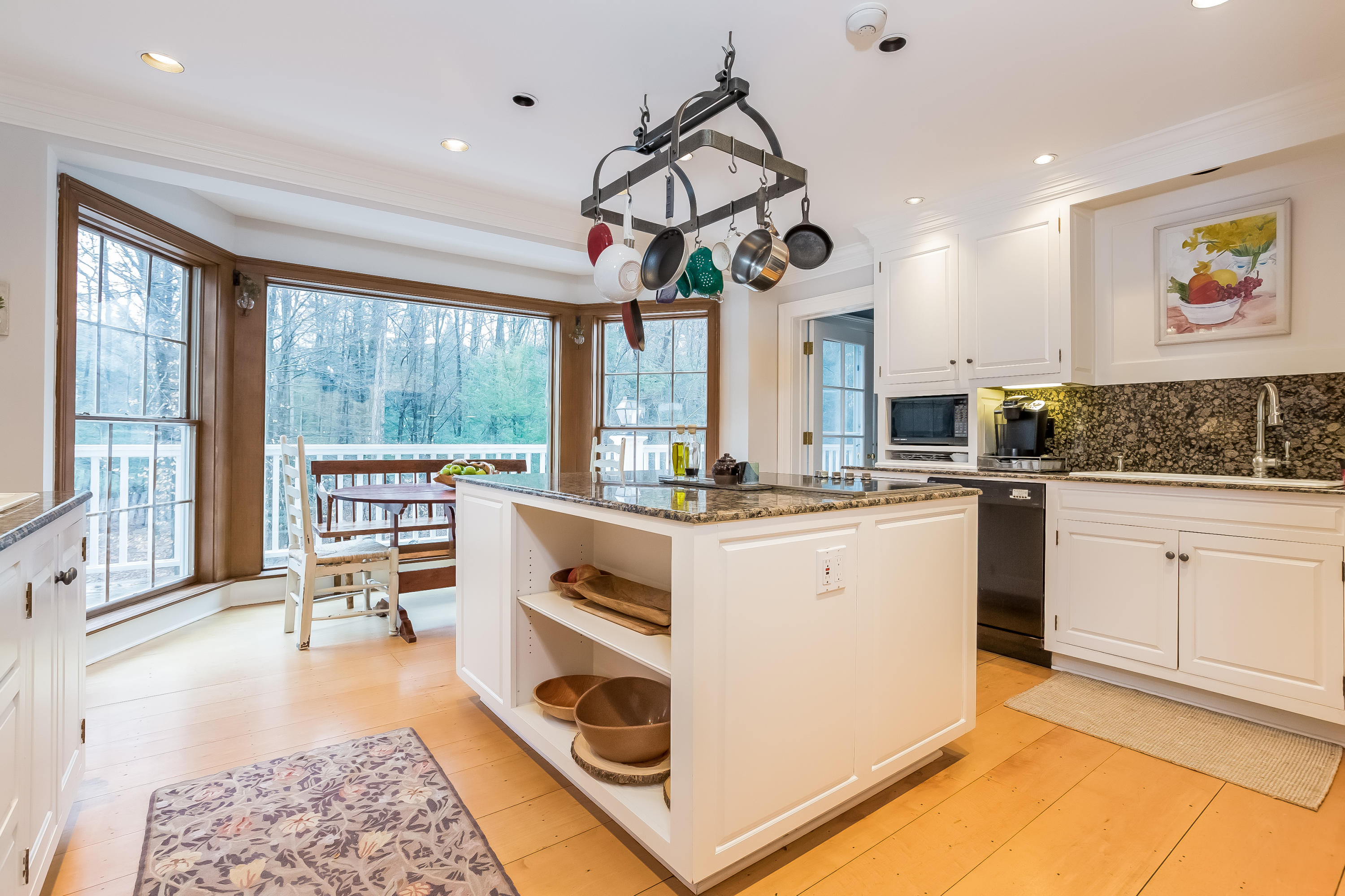 269 Valley Road New Canaan, CT 06840 - Photo 9 of 21 a kitchen with stainless steel appliances kitchen island granite countertop a stove a sink a dining table and chairs with wooden floor