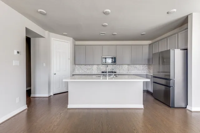a large kitchen with stainless steel appliances a sink and a refrigerator