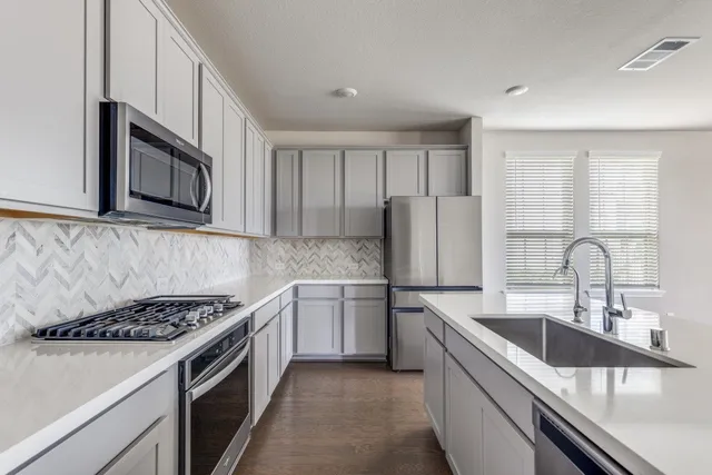 a kitchen with stainless steel appliances granite countertop a sink stove microwave and refrigerator