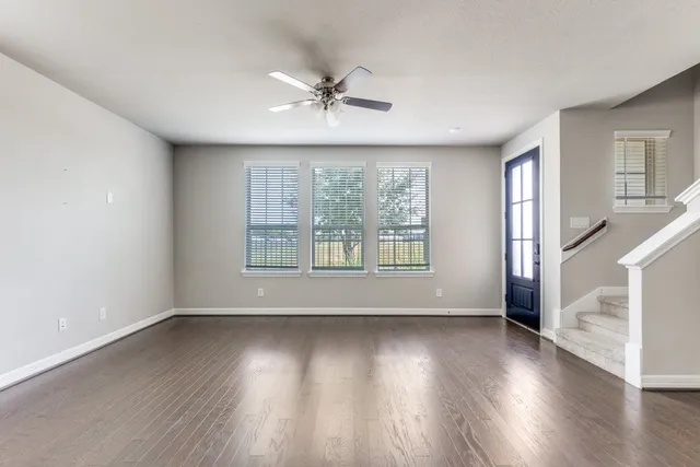 a view of an empty room with wooden floor and a window