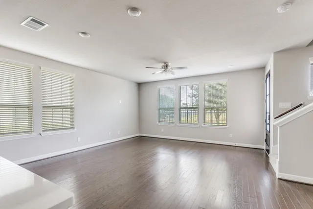an empty room with wooden floor and windows