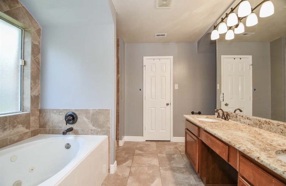 8515 Split Branch Lane Houston, TX 77095 - Photo 15 of 31 a bathroom with a tub a sink and a large mirror