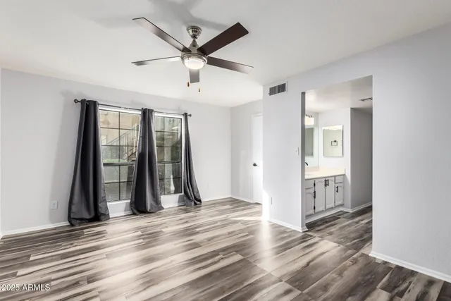 an empty room with wooden floor and a ceiling fan