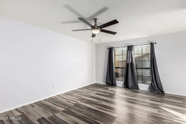 a view of a room with wooden floor and a ceiling fan