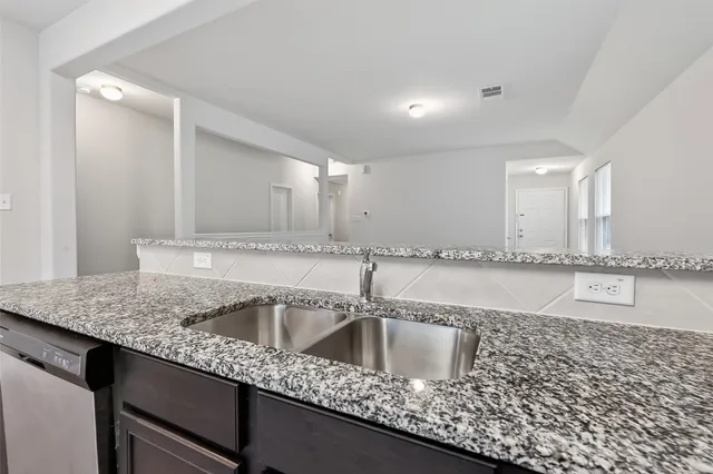 a kitchen with stainless steel appliances granite countertop a sink and a white cabinets