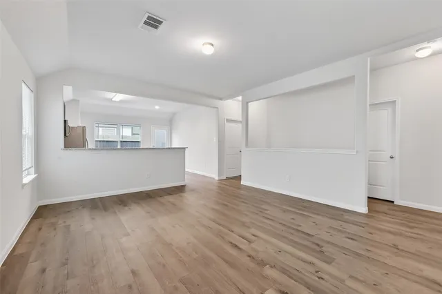 an empty room with wooden floor and windows
