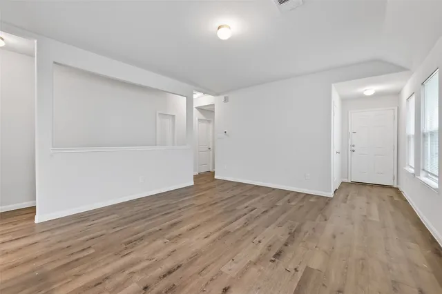 a view of an empty room with wooden floor and closet