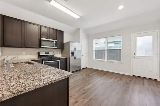 a kitchen with granite countertop wooden cabinets a refrigerator and a sink