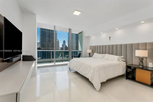 a large white bed sitting in a room next to a window