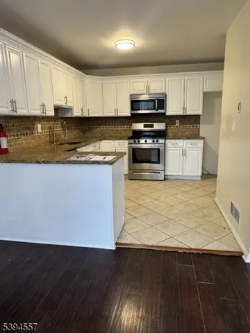 a kitchen with granite countertop a stove a sink and a microwave