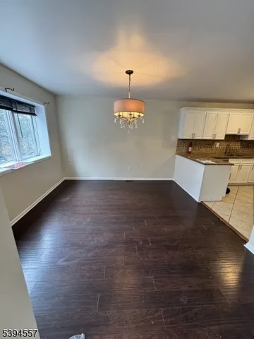 an empty room with wooden floor windows and entrance