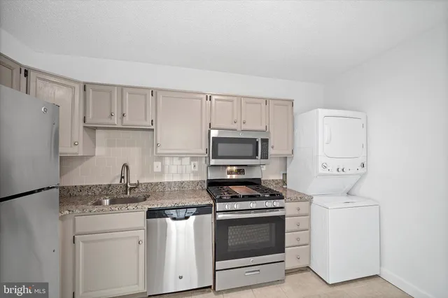 a kitchen with stainless steel appliances granite countertop a stove a refrigerator and a microwave
